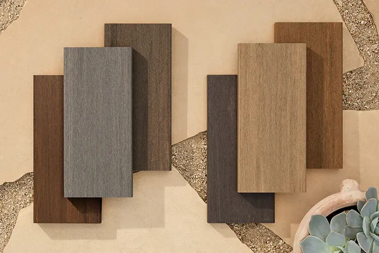 Overhead shot of six TimberTech deck samples from the Vintage Collection stacked on each other on large tan tiles in the desert